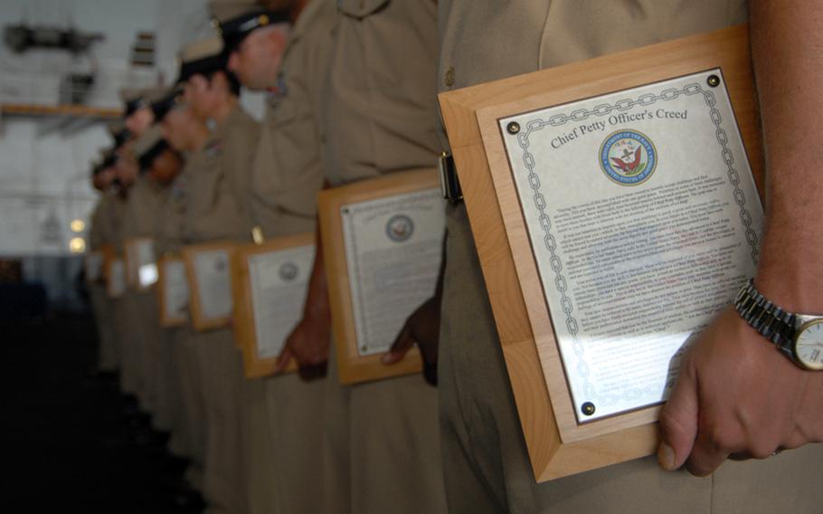 In this file photo from 2007, chief petty officers hold on to a plaque scribed with the Chief Petty Officer's Creed during their pinning ceremony aboard Nimitz-class aircraft carrier USS Dwight D. Einsenhower.