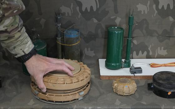 A Cypriot National Guardsman handles an inert landmine that is part of a display of inert rockets, artillery shells and other munitions as part of a training course of Ukrainian personnel in the disposal of landmines and other explosive ordnance in Cyprus, at an army base, in Nicosia, Thursday, Nov. 14, 2024. (AP Photo/Petros Karadjias)