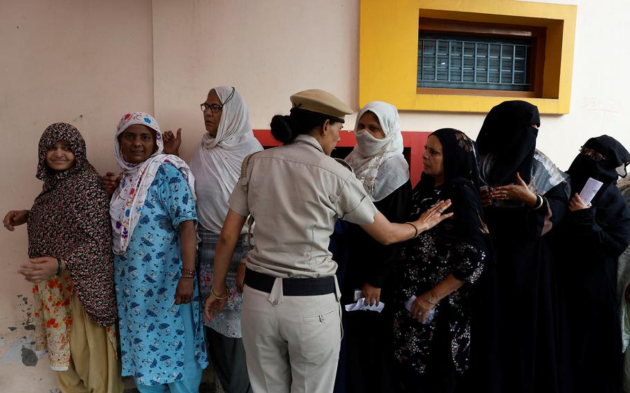 A police officer asks women to maintain a line as they wait to cast their votes at a polling station during the sixth phase of India’s general election in New Delhi, India, May 25, 2024.