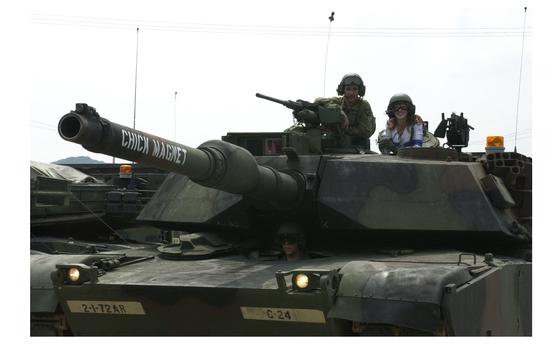 Camp Casey, South Korea, Jul. 4, 2002: A Dallas Cowboy Cheerleader rides with the crew of an M1A-1 Abrams tanks at Camp Casey, Korea.  The Dallas Cowboy Cheerleaders were visiting Camp Casey as part of the Wayne Newton Holiday USO tour to Korea. 

META TAGS: 2nd Infantry Division; USO; Dallas Cowboys; cheerleaders; NFL; U.S. Army; 