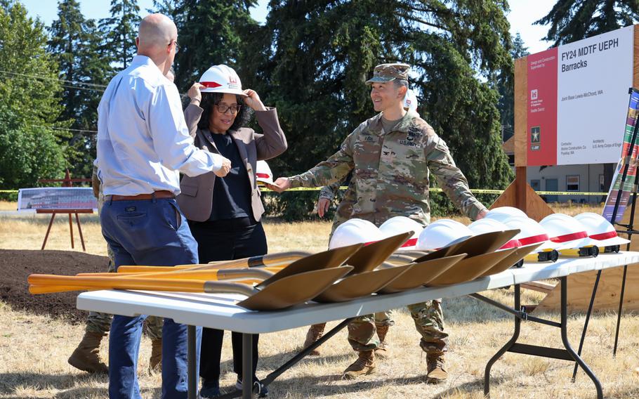 Assistant Army Secretary Paul Farnan, Rep. Marilyn Strickland, D-Wash., and Army Col. Kent Park, Joint Base Lewis-McChord garrison commander, pick out hard hats and shovels for groundbreaking ceremony of a new barracks using sustainable building materials and environmentally friendly construction techniques. The pilot program could be replicated at Army bases around the world. 