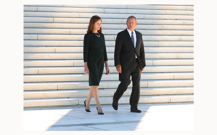 U.S. Supreme Court Associate Justice Amy Coney Barrett and Chief Justice John Roberts walk down the steps of the west side of the Supreme Court on Oct. 1, 2021, in Washington, D.C. 