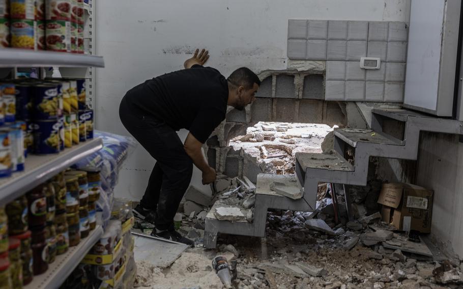 A man inspects the damage inside a supermarket in Tamra