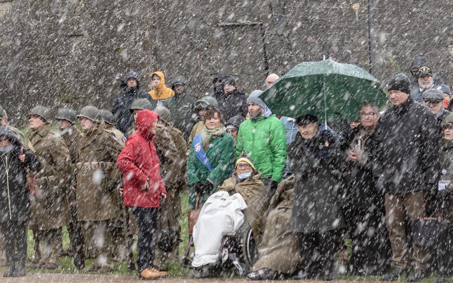 A group of people, including Ceo Bauer, honor soldiers of the 95th Infantry Division while it snows.