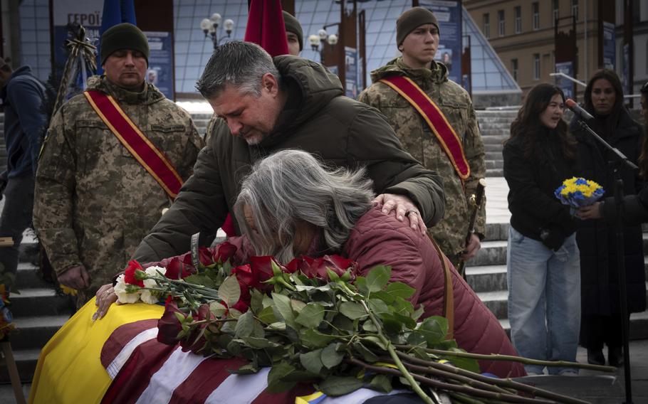 Parents of U.S. Marine Corps veteran Ethan Hertweck, 21, lay hands on a coffin during a funeral ceremony.