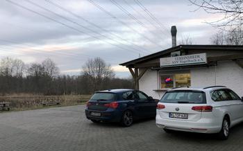 Two cars parked in front of a small restaurant building with a take-out window.