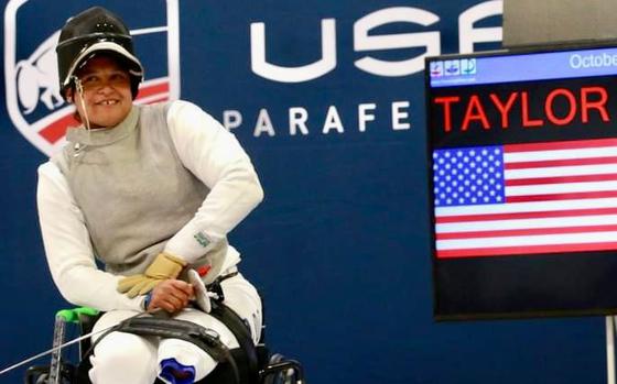 Marine veteran Jataya Taylor sits in her wheelchair in front of a USA Parafencing sign.