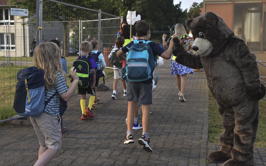 Aukamm Elementary School mascot "Bruno Bear" high-fives a third grade student as the class starts their first day of school, Aug. 19, 2024, in Wiesbaden, Germany.