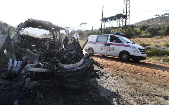 An ambulance drives past a vehicle that burned in the town of Masyaf, Syria, Monday, Sept. 9, 2024. Syrian state news agency SANA says that Israeli strikes hit several areas in central Syria Sunday night, damaging a highway in Hama province and sparking fires. (AP Photo/Omar Sanadiki)