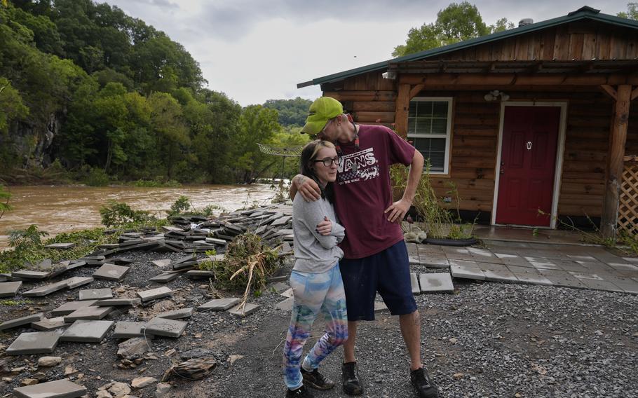 A man kisses his wife outside of their house that was damaged from Hurricane Helene.