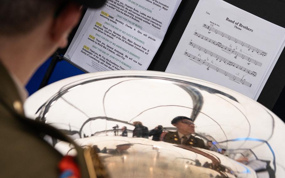 A band member looks past his instrument to see music sheets.