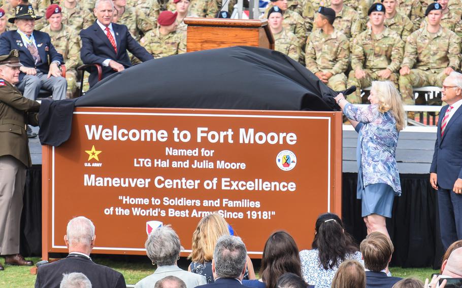 Three people unveil new base sign as crowd looks on.