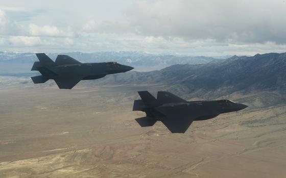 F-35A Lightning II fly with clouds and mountains in the background. 