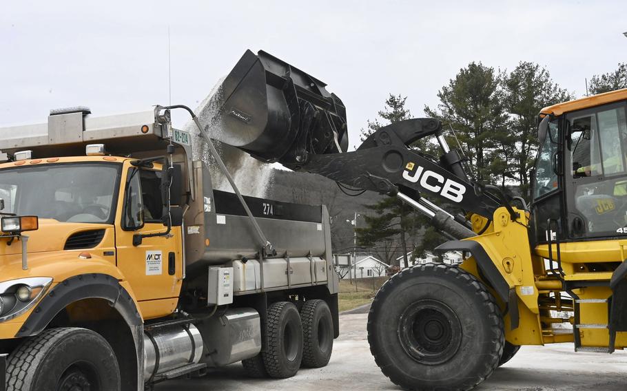 Maryland Department of Transportation employees use a backhoe to load a truck with salt 