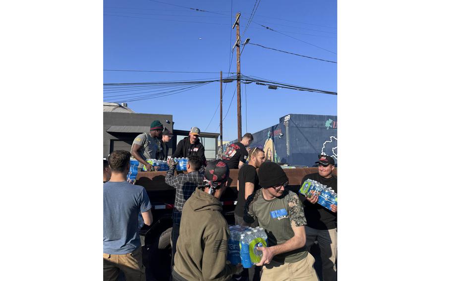 Fort Irwin soldiers and volunteer personnel unload packs of bottled water from a truck 