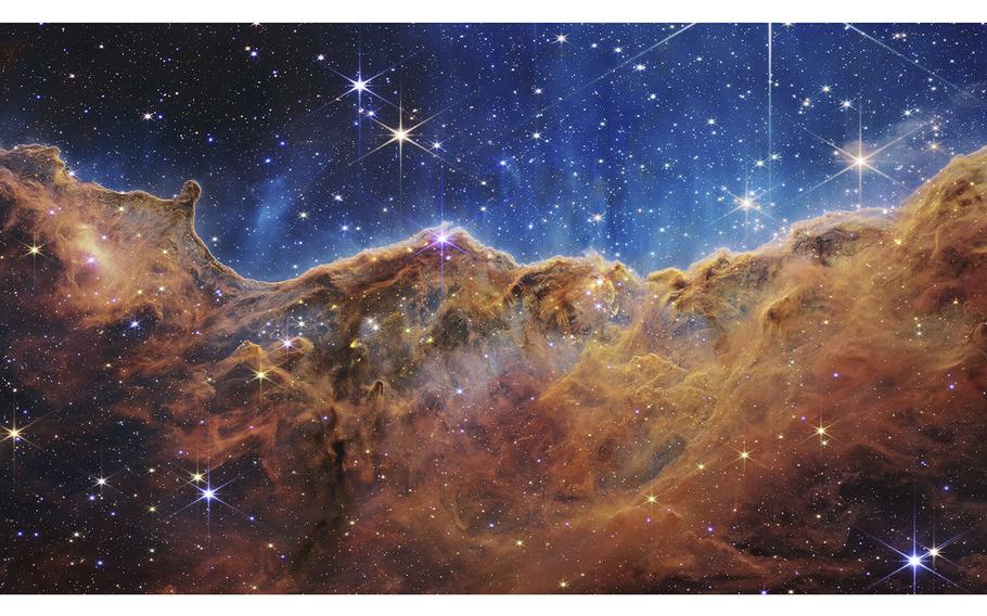 In this handout photo provided by NASA, a landscape of mountains and valleys speckled with glittering stars is actually the edge of a nearby, young, star-forming region called NGC 3324 in the Carina Nebula, on July 12, 2022, in space. Captured in infrared light by NASA’s new James Webb Space Telescope, this image reveals for the first time previously invisible areas of star birth.  