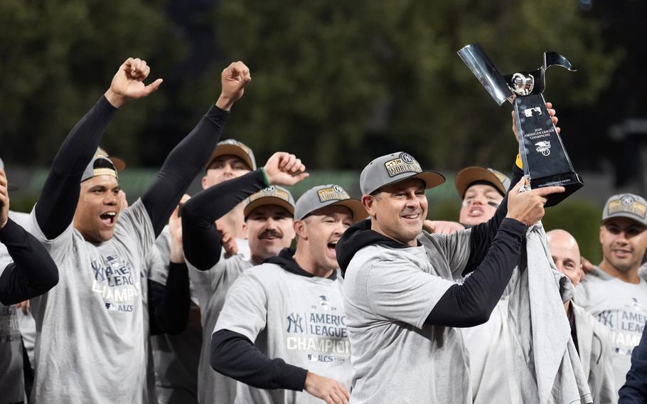 Yankees players celebrate with the American League trophy after defeating the Cleveland Guardians.