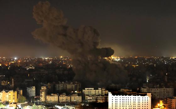 Dark smoke rises into the night sky above damaged buildings in Beirut, Lebanon.