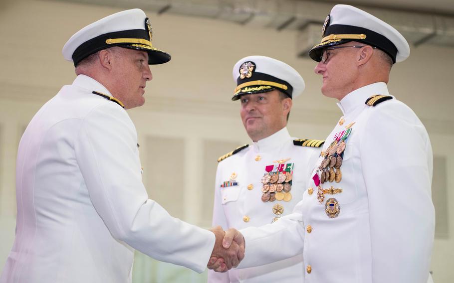 Rear Adm. Brad Collins, left, head of Navy Region Europe, Africa, Central, shakes hands Aug. 1, 2024, with the outgoing commander of  Naval Support Activity Souda Bay in Greece, Capt. Odin Klug, as new commander Capt. Stephen Steacy watches. 