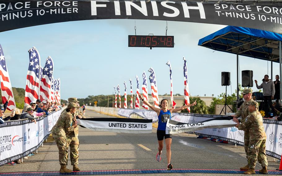 The first-place runner among female competitors of the T-Minus 10-Miler marathon is seen breaking through a ribbon that reads “United States Space Force” as she crosses the finish line with her arms outstretched.