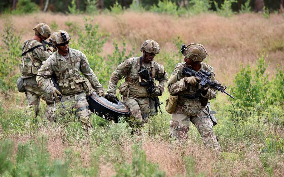 Soldiers carry a tank roadwheel to simulate the necessities of emergency maintenance during training at Drawsko Combat Training Center in Poland on July 2, 2024.