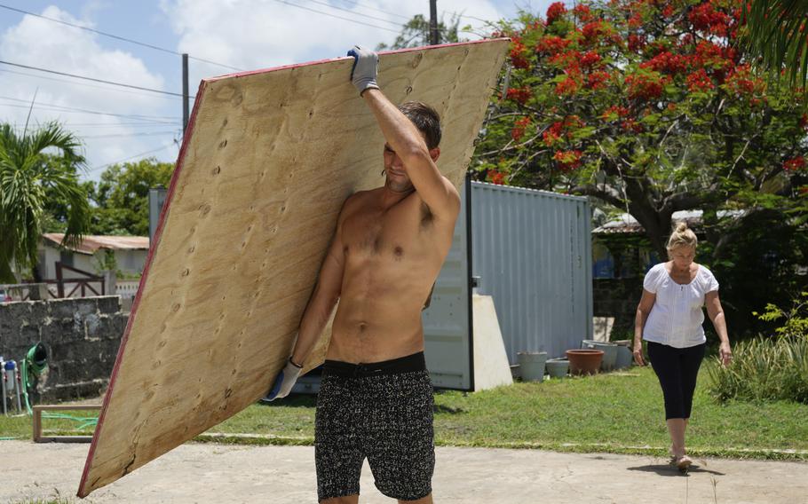 A resident carries wood to cover his house’s windows in preparation for Hurricane Beryl, in Bridgetown, Barbados, Sunday, June 30, 2024. 
