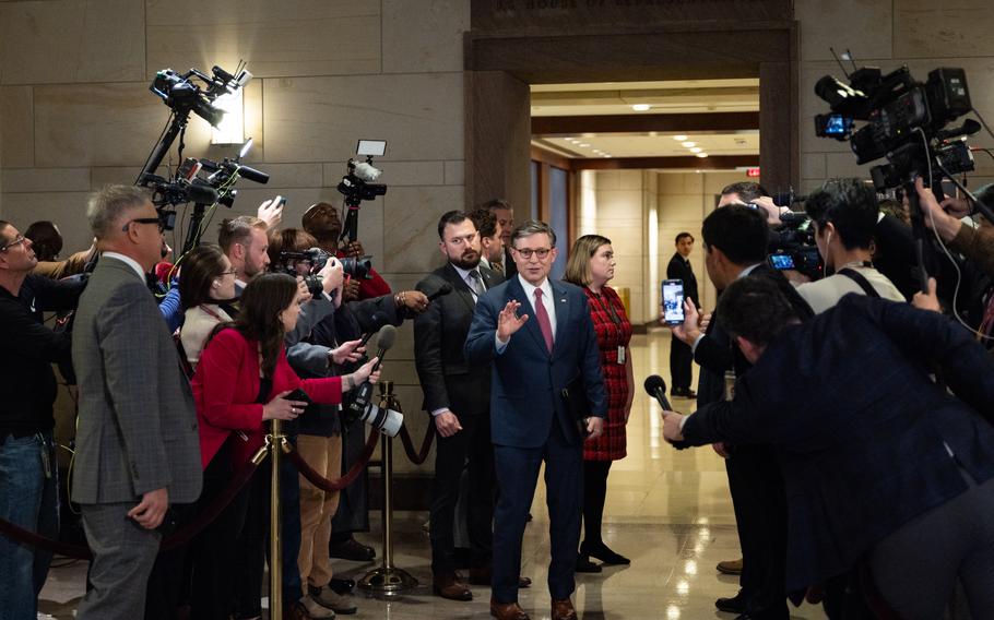 House Speaker Mike Johnson raises his hand an answers questions from media members on both sides.