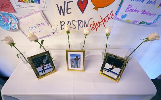 Six white roses adorn three photographs of victims of an aircraft crash sitting on a table covered by a white cloth.