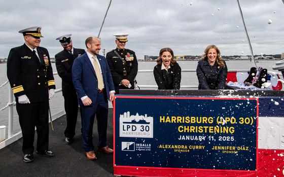 Sponsors for the new ship USS Harrisburg break bottles as part of the christening.