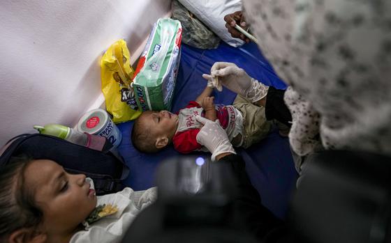 A health worker administers a polio vaccine to a child at a hospital in Khan Younis, Saturday, Aug. 31, 2024. (AP Photo/Abdel Kareem Hana)