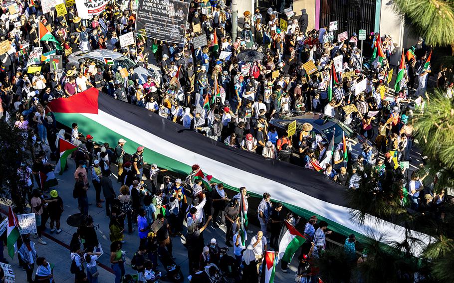 Protesters carry a large Palestinian flag through downtown Los Angeles to protest the death toll in the conflict in Gaza.