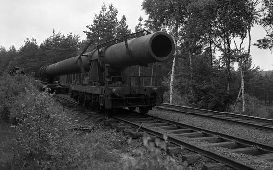 A massive Nazi Germany produced railway gun is being disassembled in the woods near Grafenwohr, Germany by American forces in July 1949.  The deployment of the gun by the Germans was an enormous endeavor. It took five trains with a total length of 1,653 meters (~5,423 ft) to transfer the gun parts to the front. Two construction cranes and some 250 men were needed for to set it up and get it fire ready – a process that took several weeks.