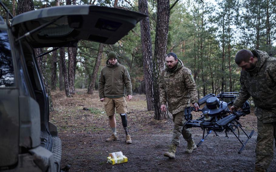 A soldier with a prosthetic leg stands near a vehicle.