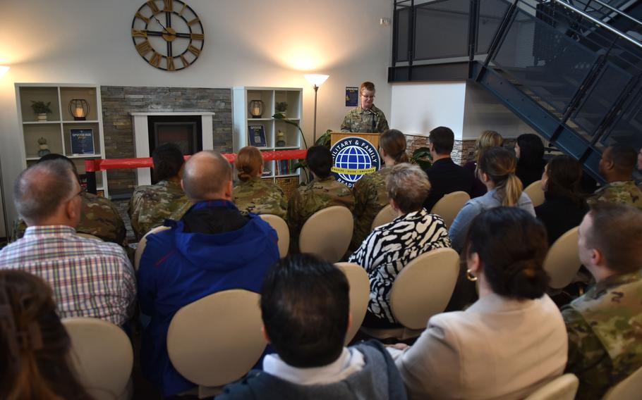 The 86th Airlift Wing commander stands at a podium discussing the origin of the spouse hub at its grand opening.