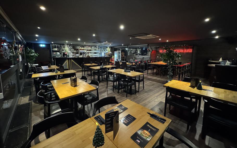 A dimly lit testaurant interior has six or eight wooden-topped tables.