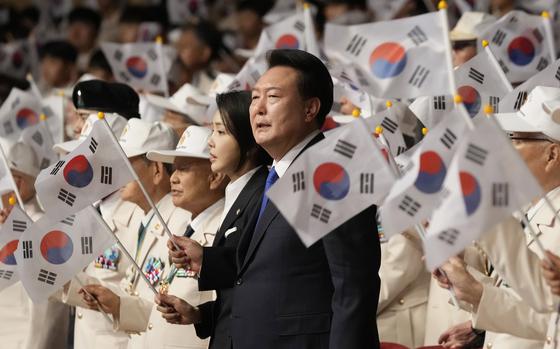 South Korean President Yoon Suk Yeol, center right, his wife Kim Keon Hee wave the national flags during a ceremony to mark the 74th anniversary of the outbreak of the Korean War in Daegu, South Korea, Tuesday, June 25, 2024. 