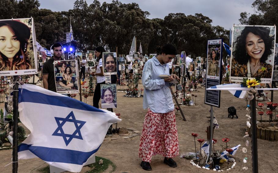 A young woman prays amid portraits affixed to wooden sticks of those killed on Oct. 7 near Kibbutz Re’em, Israel.