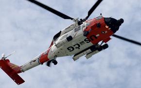 White clouds and blue sky above a Coast Guard helicopter.