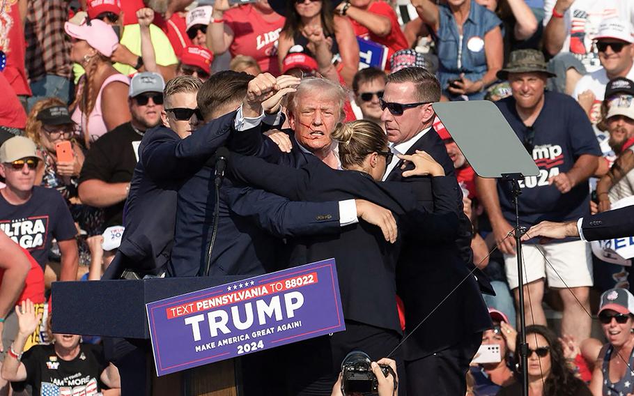 Blood drips down the face of Republican candidate former President Donald Trump as Secret Service agents lead him off the stage  in Butler, Pennsylvania, on July 13, 2024, after he survived an assassination attempt.