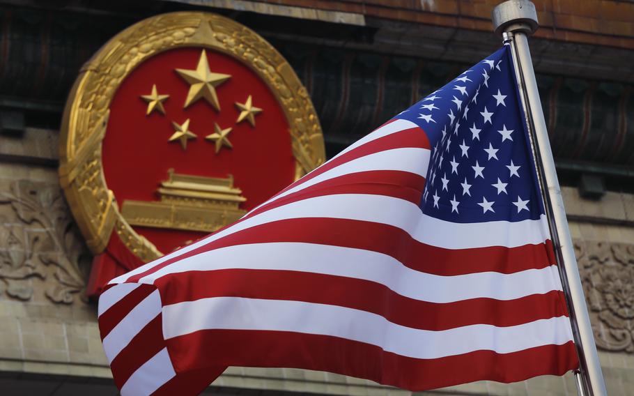 An American flag waves just in front of China’s national emblem outside the Great Hall of the People in Beijing.