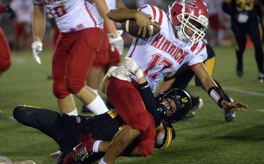 Kinnick's Atsushi Blocton gets dragged down by Kadena's Michael Smith.