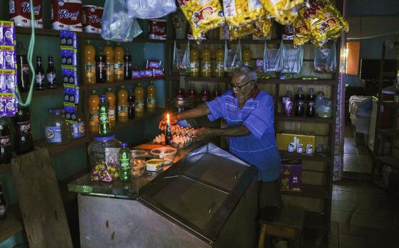 A man lights a candle in his shop during a blackout in Caracas, Venezuela, on Aug. 30, 2024.