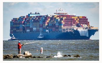 The container ship Dali approaches the Chesapeake Bay Bridge on its way to Norfolk as a man fishes at Sandy Point State Park. Ninety days ago the ship hit a support pier of the bridge causing a catastrophic collapse. (Jerry Jackson/Staff)