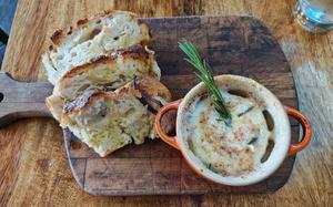 Baked buffalo milk Camembert served with ciabatta bread at Limoncello, an Italian restaurant and deli in Cambridge, England. The cheese dip is topped with rosemary. 
