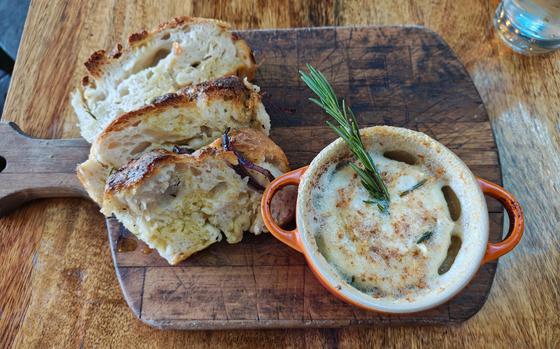 Baked buffalo milk Camembert served with ciabatta bread at Limoncello, an Italian restaurant and deli in Cambridge, England. The cheese dip is topped with rosemary. 
