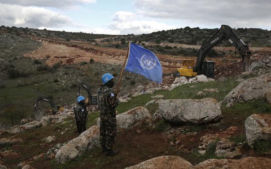 FILE - UN peacekeepers hold their flag, as they observe Israeli excavators attempt to destroy tunnels built by Hezbollah, near the southern Lebanese-Israeli border village of Mays al-Jabal, Lebanon, Dec. 13, 2019. (AP Photo/Hussein Malla, File)