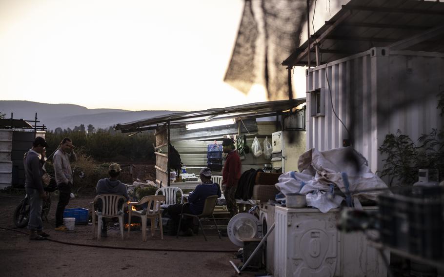 A camp for farmworkers with plastic chairs, fans, electronics and a few workers.