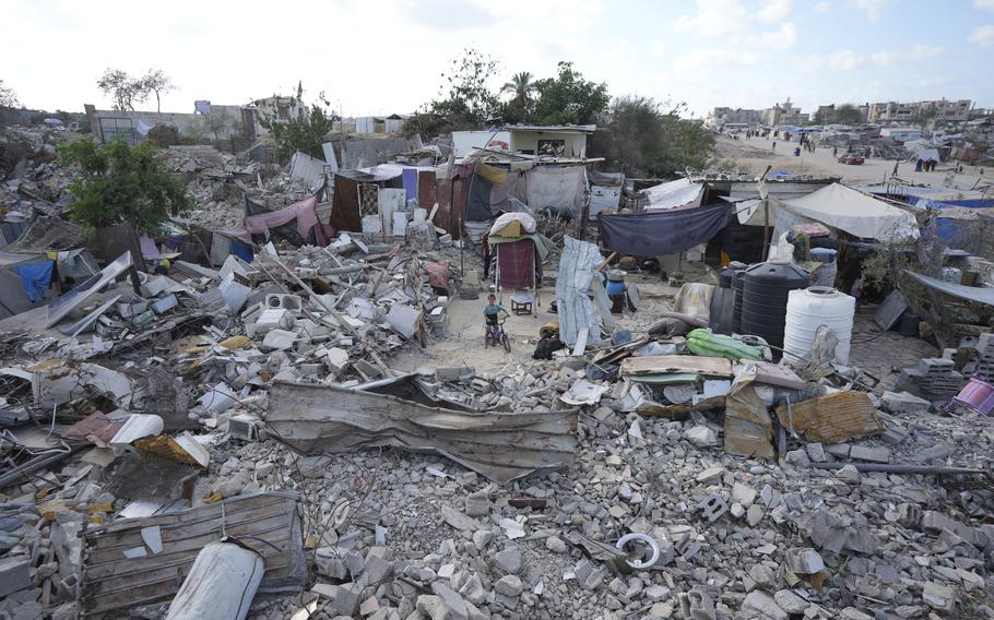 A child rides his bicycle in small, cleared area of bomb debris.