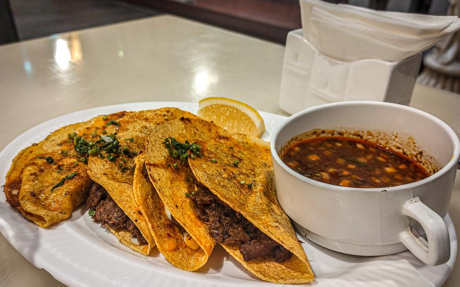 Quesabirria tacos and sauce on a platter.