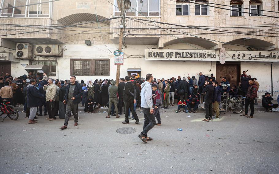 Palestinians line up in front of Bank of Palestine ATMs to withdraw money after the Palestinian Authority deposited salaries, in Rafah in the southern Gaza Strip on Monday. 